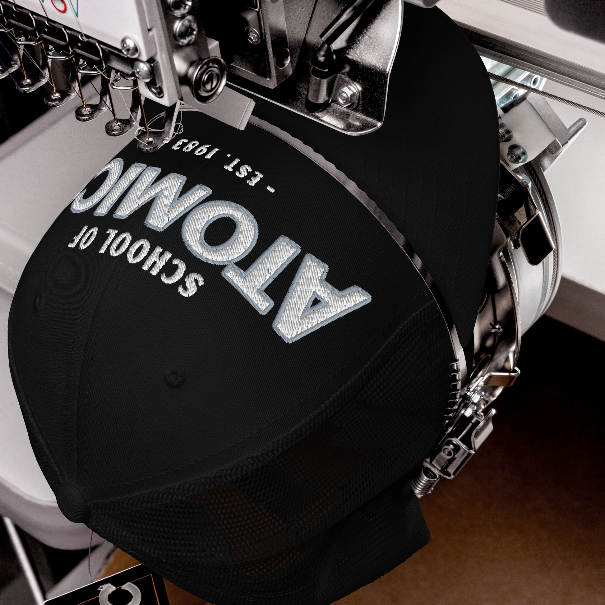 Black School Of Atomics trucker cap with embroidered text and mesh back.