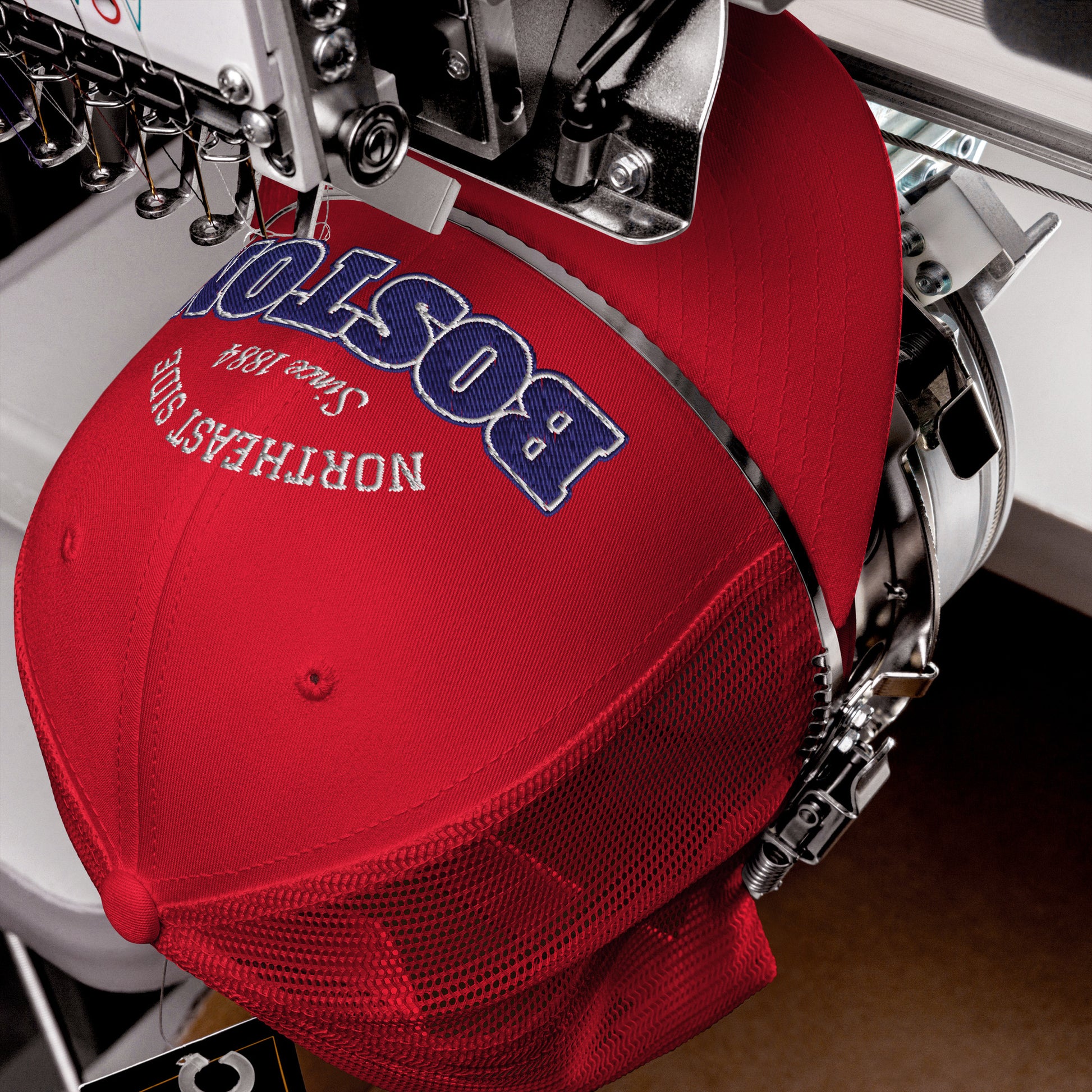 Red trucker cap with "Boston" and "Northeast Side" embroidered in blue and white.